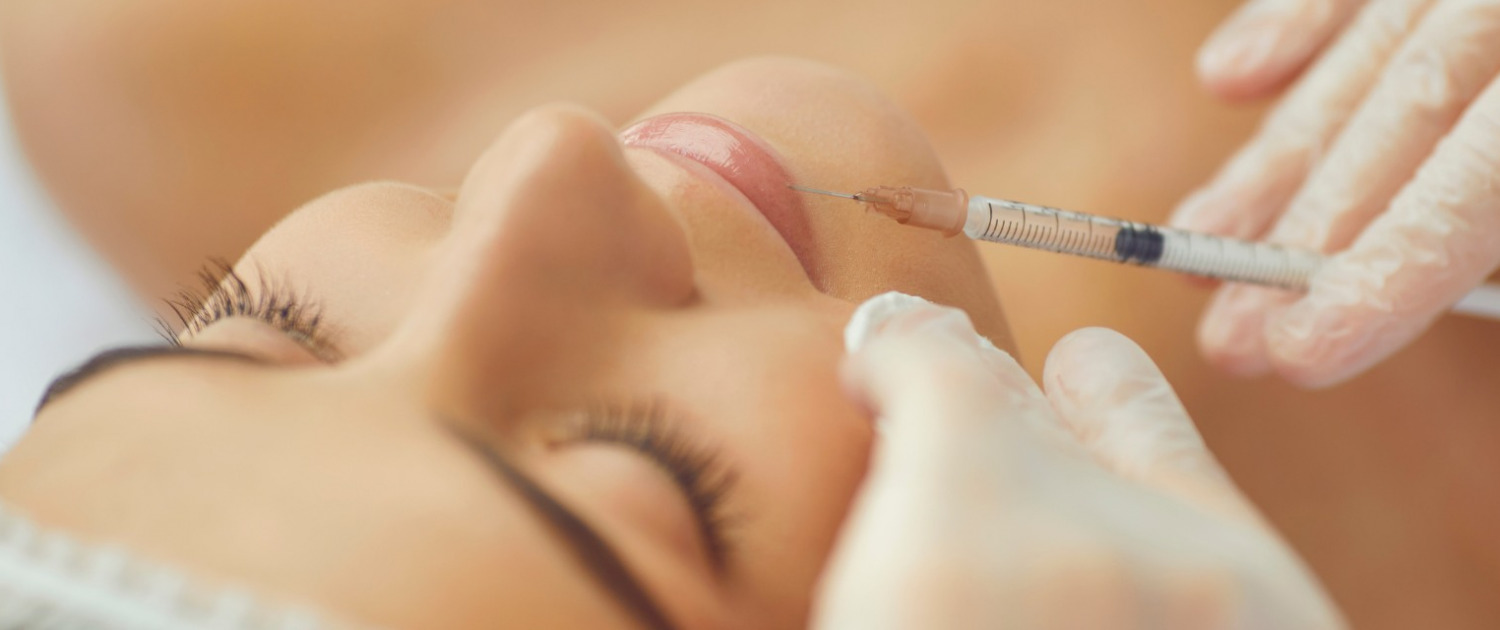 russian-lips-injektionstechnik-1 Die Nahaufnahme einer Lippeninjektion bei einer Frau, die mit geschlossenen Augen auf dem Rücken liegt, während die Spritze an ihre Lippen geführt wird.